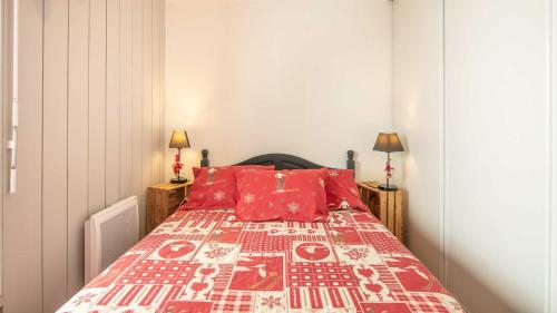 ein Schlafzimmer mit einem Bett mit roten Kissen in der Unterkunft Les Tetras - 63 - Studio moderne - 4 pers in Saint-Sorlin-dʼArves