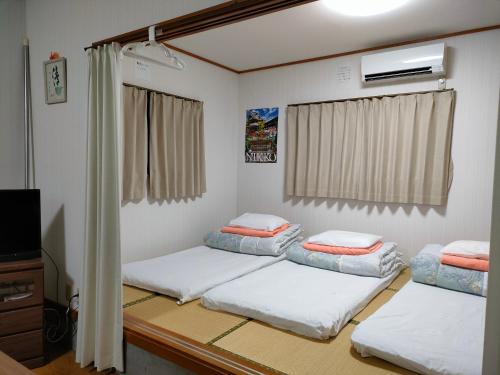 a room with three beds and a television at Guesthouse Maple Nikko in Nikko