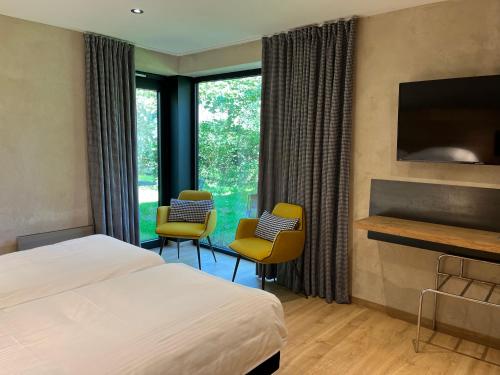 een hotelkamer met een bed en twee stoelen en een open haard bij Logis Hostellerie De La Claire Fontaine in La-Roche-en-Ardenne