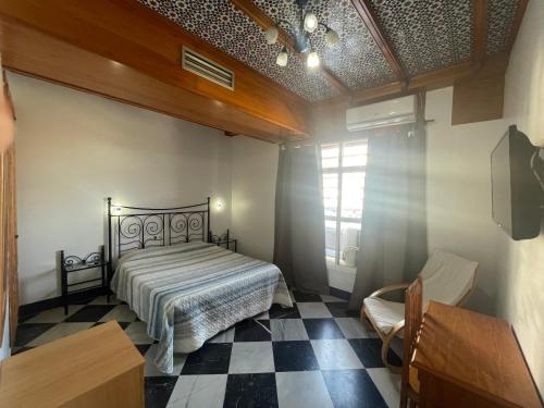 1 dormitorio con 1 cama y suelo a cuadros en El Ancla, en Alcalá del Río