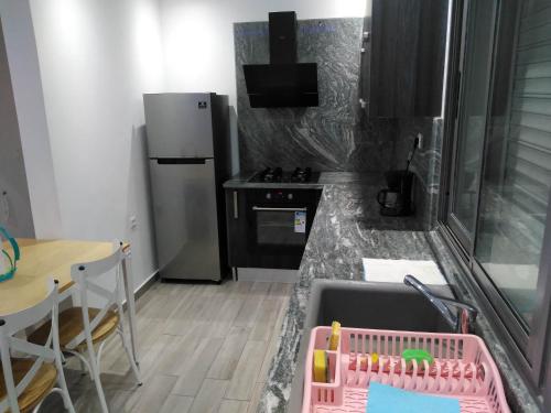 a kitchen with a sink and a table and a refrigerator at Residence Inès djerba Appartement de Lux in Houmt Souk