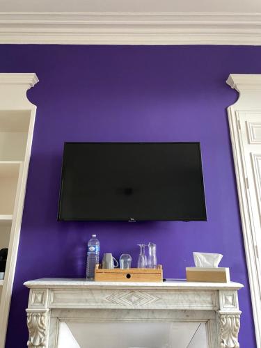 a flat screen tv on a purple wall at Chambres d'Hôtes Au coin du spa in Boulogne-sur-Mer