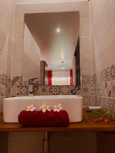 a bathroom sink with flowers on it in front of a mirror at La Caza Léo - 120m² - Piscine vue sur mer in Étang-Salé