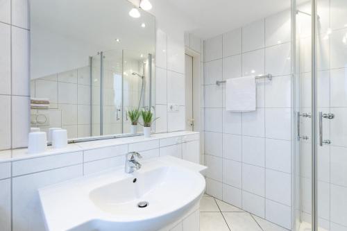 La salle de bains blanche est pourvue d'un lavabo et d'une douche. dans l'établissement M3 - Apartmenthaus Marienburger Str 4 - FERIENDOMIZIL HOLLICH, à Grömitz