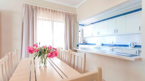 a kitchen with a table with a vase of pink flowers at Alfagar Cerro Malpique in Albufeira