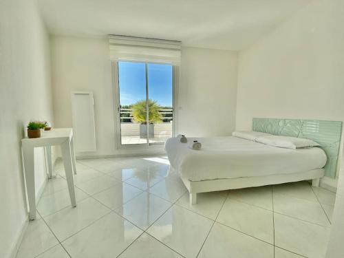 ein weißes Zimmer mit einem Bett und einem Fenster in der Unterkunft Le Swing N01 toit terrasse in La Grande-Motte
