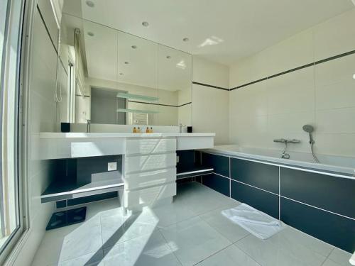 a white bathroom with a sink and a tub at Le Swing N01 toit terrasse in La Grande-Motte