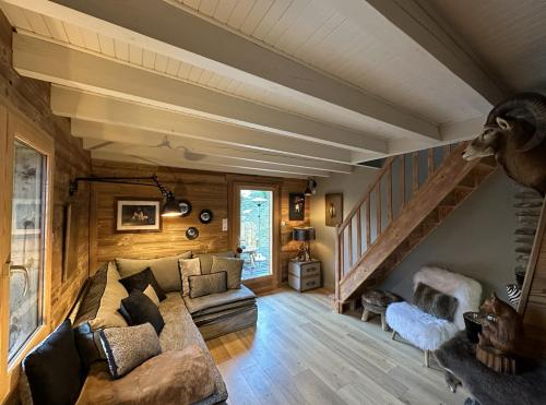 ein Wohnzimmer mit einem Sofa und einer Treppe in der Unterkunft Chalet de l'Ours : 4 étoiles-spa-proche des pistes in La Clusaz