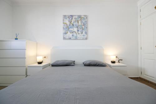a white bedroom with a large bed with two pillows at Beautiful Apartment by the Sea in Playa San Juan in Playa de San Juan