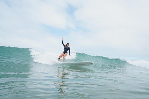 una mujer montando una ola en una tabla de surf en el océano en Surf ou Golf House a quelques pas de l'océan, en Moliets-et-Maa