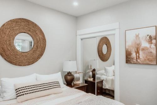 a white bedroom with a bed and two mirrors at Urban Rustic Getaway in Corvallis