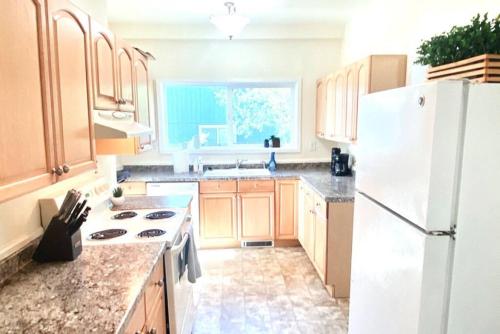 a kitchen with wooden cabinets and a white refrigerator at The Cheerful Bungalow Family Home OSU PNW in Corvallis