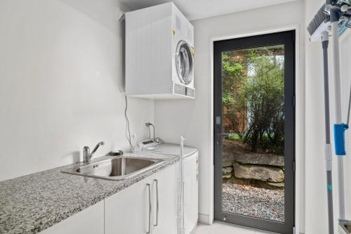 a white kitchen with a sink and a door at Urban Oasis - Wanaka Holiday Home in Wanaka