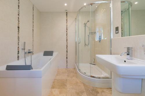 a bathroom with a shower and a sink and a tub at Beachcroft in St Ives