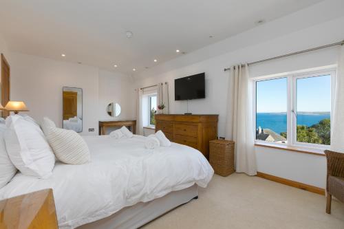 a white bedroom with a large bed and a window at Beachcroft in St Ives