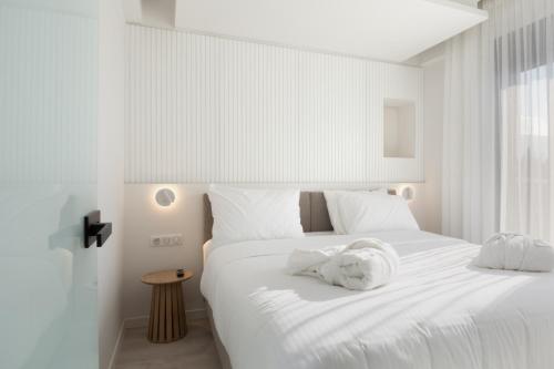 um quarto com uma cama branca com uma toalha em LUX&EASY Acropolis Suites em Atenas