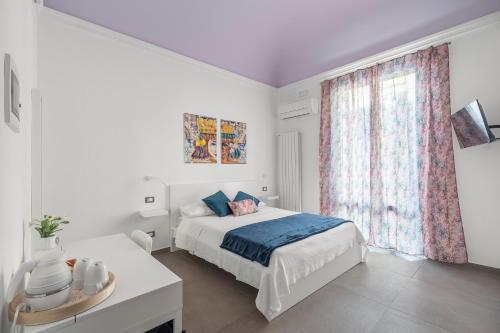 a white bedroom with a bed and a window at MolteVolte Rooms in Palermo