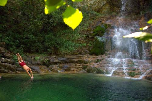 a man standing in the water in front of a waterfall at Hotel Villa Drosos in Litochoro