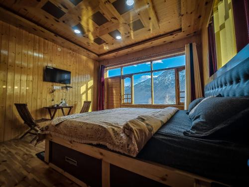 a bedroom with a bed and a large window at The Alpinist cafe and Retreat in Kaza