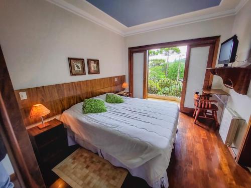 a bedroom with a bed and a large window at Pousada Victoria Villa By Nacional Inn - A 800 metros da Vila Capivari in Campos do Jordão