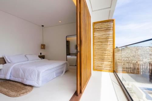 a bedroom with a bed and a large window at Mikiki Lifestyle Hotel in Barra Grande