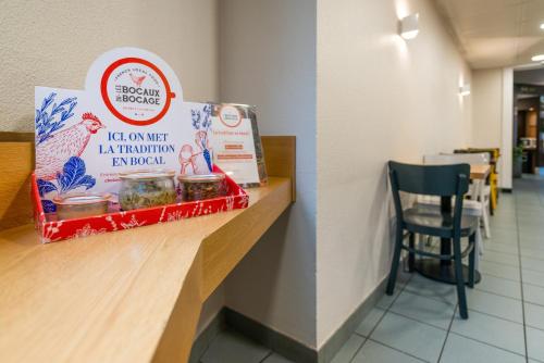 a counter in a restaurant with a sign and a chair at B&B HOTEL Cholet Sud in Cholet