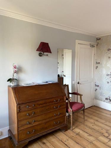 a bedroom with a dresser and a lamp and a chair at Chambres d'Hôtes Au coin du spa in Boulogne-sur-Mer