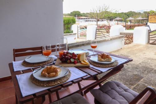 a wooden table with food and glasses of wine at Apartamento Tramuntana 3 in Cala Blanca
