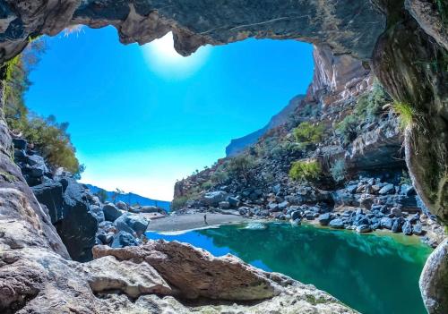 a view of a river through a cave in a canyon at Balcony walk rest house Jabal shams in Sa‘ab Banī Khamīs
