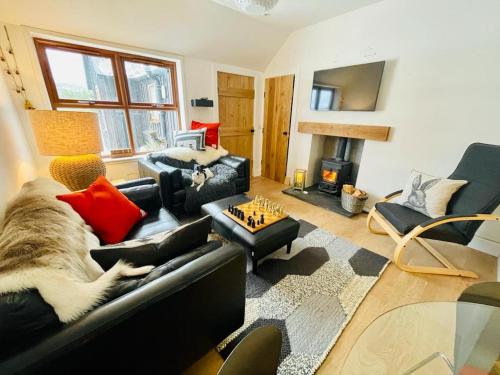 a living room with a black leather couch and a chess at Stag's Hide in Aviemore