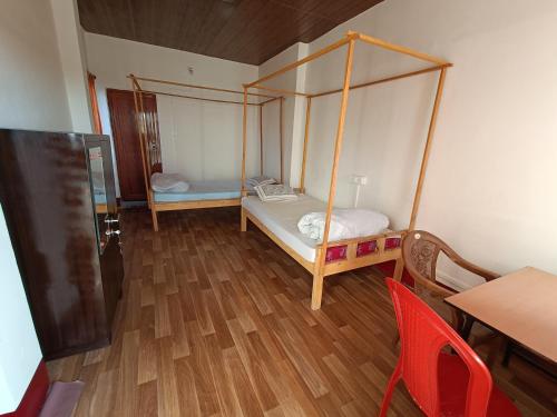 Habitación pequeña con cama y mesa en Manipur House en Imphal