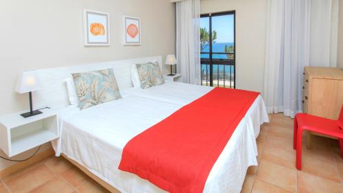 una camera da letto con un grande letto bianco con una coperta rossa di Alfagar Village ad Albufeira