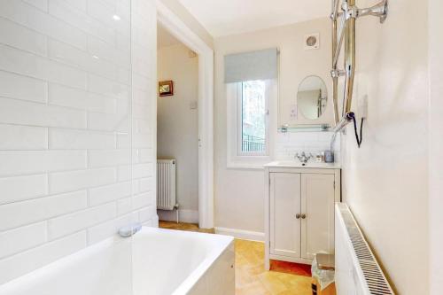 a white bathroom with a tub and a sink at Beautiful two bedroom apartment in Honor Oak in London