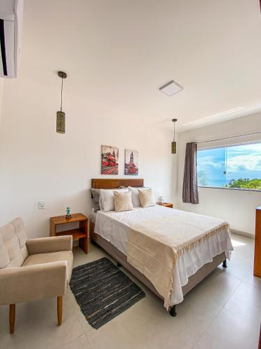 a bedroom with a bed and a chair and a window at Villa do Mar in Cayru