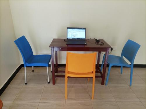 a desk with three chairs and a laptop on it at Pearl Furnished Rooms Buloba in Kampala