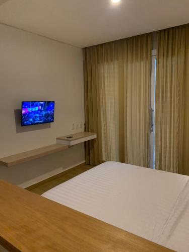 - une chambre avec un lit et une télévision murale dans l'établissement The Hita Apartement, à Seminyak