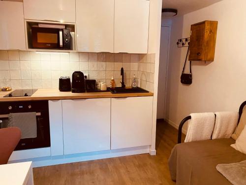 małą kuchnię z białymi szafkami i kuchenką mikrofalową w obiekcie Charmant studio avec coin nuit en mezzanine La Foux d'Allos w mieście Allos