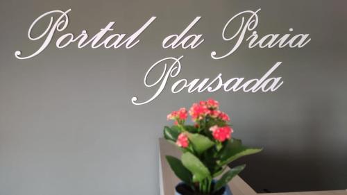 a sign for a restaurant with a vase of flowers at Pousada Portal da Praia in Capão da Canoa
