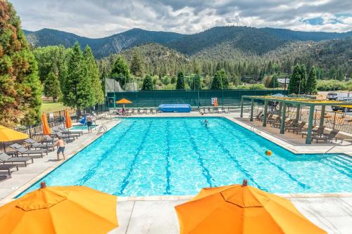 a large swimming pool with chairs and umbrellas at Pine Mountain Club Log Home with Deck and Grill! in Pine Mountain Club