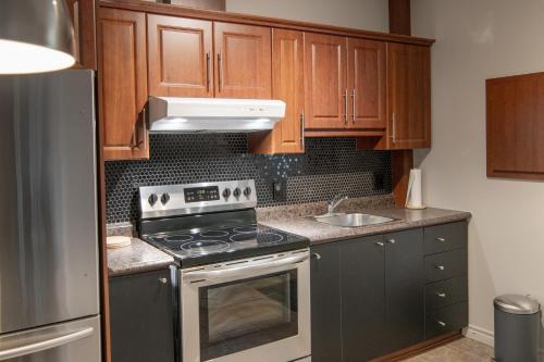 a kitchen with wooden cabinets and a stove top oven at Appartements Victoria in La Baie
