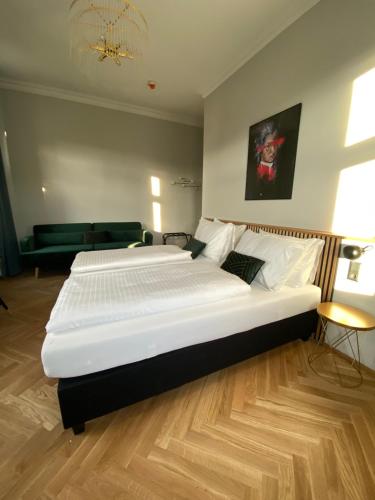 a large white bed in a room with a wooden floor at Boutique Hotel Kolbeck in Vienna