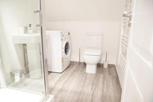 a bathroom with a toilet and a washing machine at Peaceful Luxury Apartment in Croydon