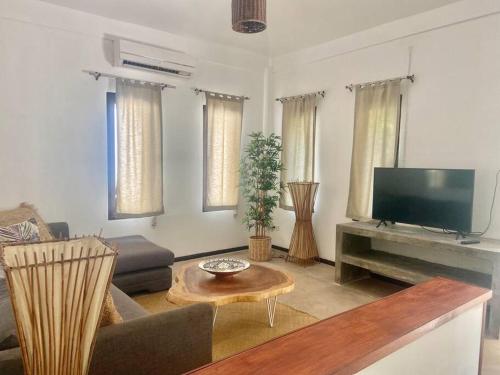 a living room with a flat screen tv and a table at Bamboo Villa in Koh Tao