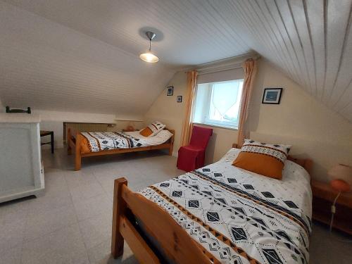 a attic bedroom with two beds and a window at Ty Coz in Saint-Ségal
