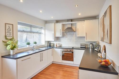 a kitchen with white cabinets and a black counter top at Host & Stay - Newsam Crescent in Eaglescliffe