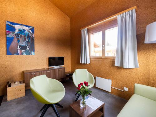 a living room with two chairs and a television at Holiday Home Komfort Aclas Maiensäss Resort-1 by Interhome in Urmein