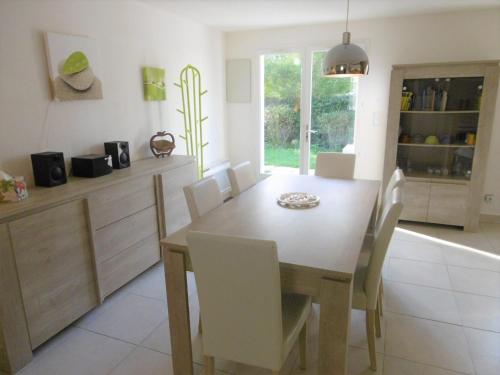 - une cuisine avec une table en bois et des chaises blanches dans l'établissement Maisonnette Nikolaz, à Sarzeau