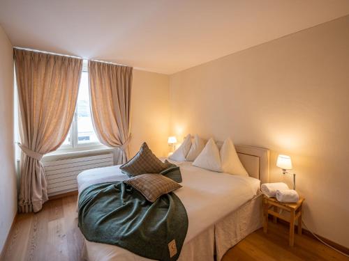 Schlafzimmer mit einem Bett mit weißer Bettwäsche und einem Fenster in der Unterkunft Apartment Chesa Crusch 7 by Interhome in Samedan