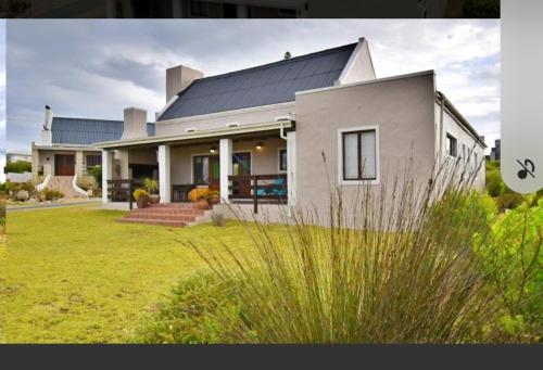 a large white house with a large yard at Four Steenbras in Struisbaai