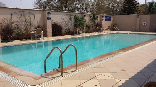 una gran piscina en un hotel con mesas y sillas en Shakespeare Court Serviced Apartments, en Lusaka